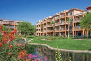 Ein Hotel mit mehreren Balkonen, einem zentralen Innenhof mit Teich und umliegender Bepflanzung.
