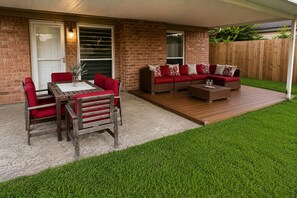 A patio with a wooden table and chairs, a sofa set, and a small coffee table. - Cozy Katy Home near Katy Mills, Restaurants, and Family Attractions (Katy)