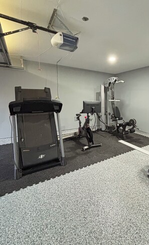 A gym with exercise equipment including a treadmill, stationary bike, and weight machines. - Cozy Katy Home near Katy Mills, Restaurants, and Family Attractions (Katy)