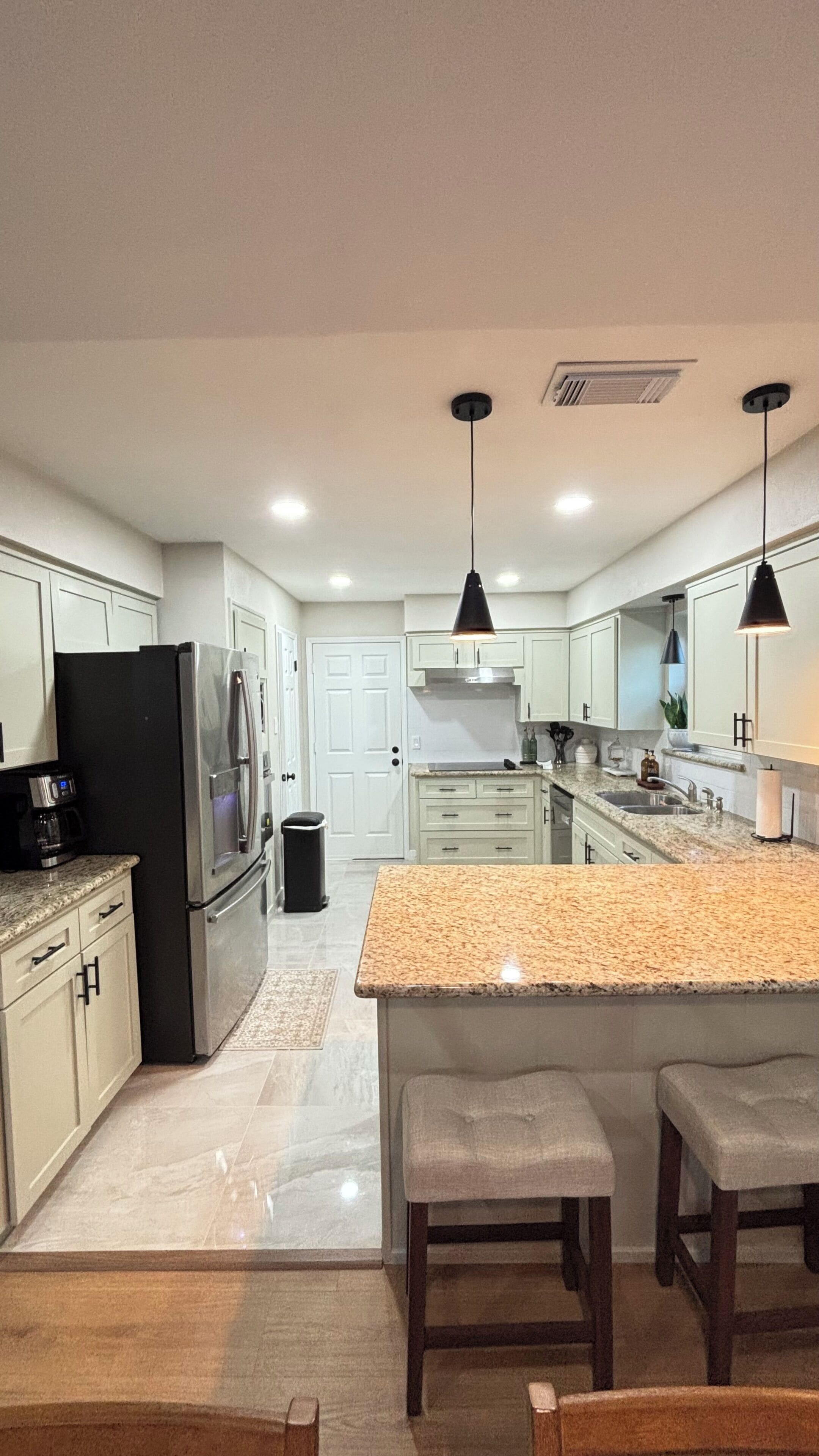 A modern kitchen with a central island, stainless steel appliances, and pendant lighting.