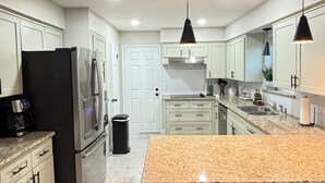 A modern kitchen with a central island, stainless steel appliances, and pendant lighting. - Cozy Katy Home near Katy Mills, Restaurants, and Family Attractions (Katy)