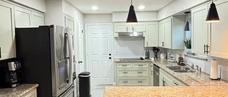 A modern kitchen with a central island, stainless steel appliances, and pendant lighting.