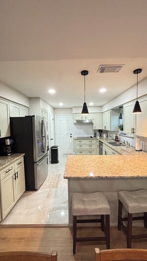 A modern kitchen with a central island, stainless steel appliances, and pendant lighting. - Cozy Katy Home near Katy Mills, Restaurants, and Family Attractions (Katy)
