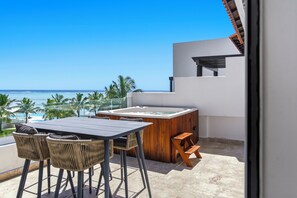 A balcony with a table and chairs, a hot tub, and a view of the ocean. - Luxury Beachfront Penthouse Punta Palmera Cap Cana (Punta Cana)
