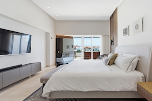 A modern bedroom with a large bed, a flat-screen TV, and a balcony with a view. - Luxury Beachfront Penthouse Punta Palmera Cap Cana (Punta Cana)