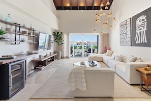 A spacious living room with a large flat-screen TV, a sofa, a coffee table, and a dining area. - Luxury Beachfront Penthouse Punta Palmera Cap Cana (Punta Cana)