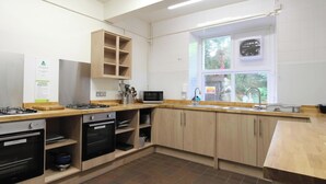 A kitchen with wooden cabinets, a gas stove, a microwave, and a window with a view of greenery.