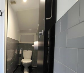 A small bathroom with a toilet, a towel dispenser, and a toilet paper holder.