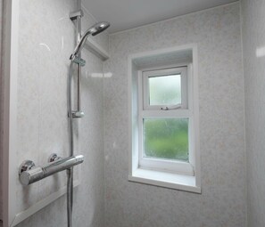 Ein Badezimmer mit Dusche, einem Fenster und einer Tür.