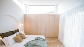 A modern bedroom with a bed, wooden wardrobe, and sheer curtains. - Casa Collection Bicheno- Casa Original (Bicheno)