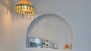 A room with a white bed, a lamp, and shelves with books and decorative items. - Casa Collection Bicheno- Casa Original (Bicheno)