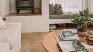 A living room with a fireplace, a sofa, a window with curtains, and a coffee table with books. - Casa Collection Bicheno- Casa Original (Bicheno)