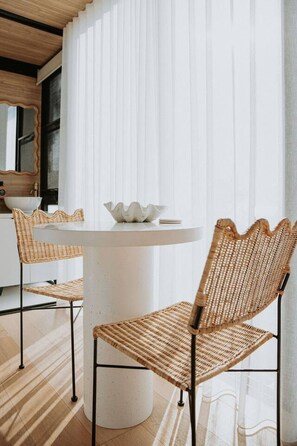 A modern interior with a round table, two wicker chairs, and a white vase. - Casa Collection Bicheno ~ The Bambino (Bicheno)