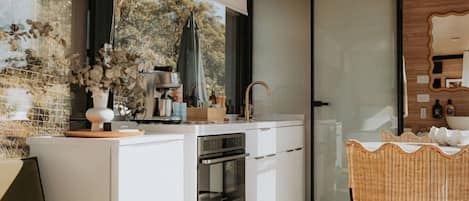 Una cocina moderna con horno empotrado, cafetera y lavabo.