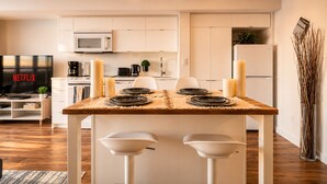 A modern kitchen with a dining table set for four, a TV displaying 'NETFLIX,' and a microwave. - Waterfront Grand Escape (Toronto)