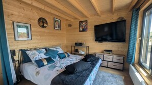 Un dormitorio con paneles de madera, una cama, un televisor y obras de arte en las paredes.