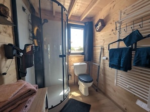 A compact bathroom with a glass shower enclosure, a toilet, and a towel rack with folded towels. - The Mallard - ORMANCEY (ORMANCEY)