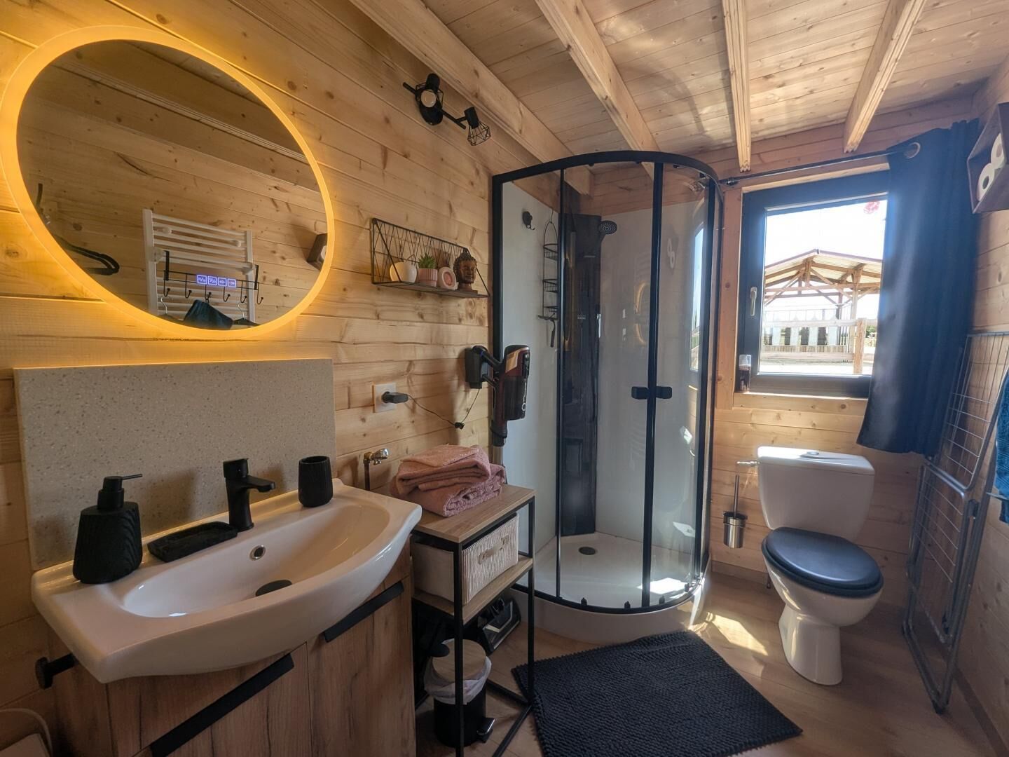 Een houten badkamer met een wastafel, spiegel, douche en toilet.