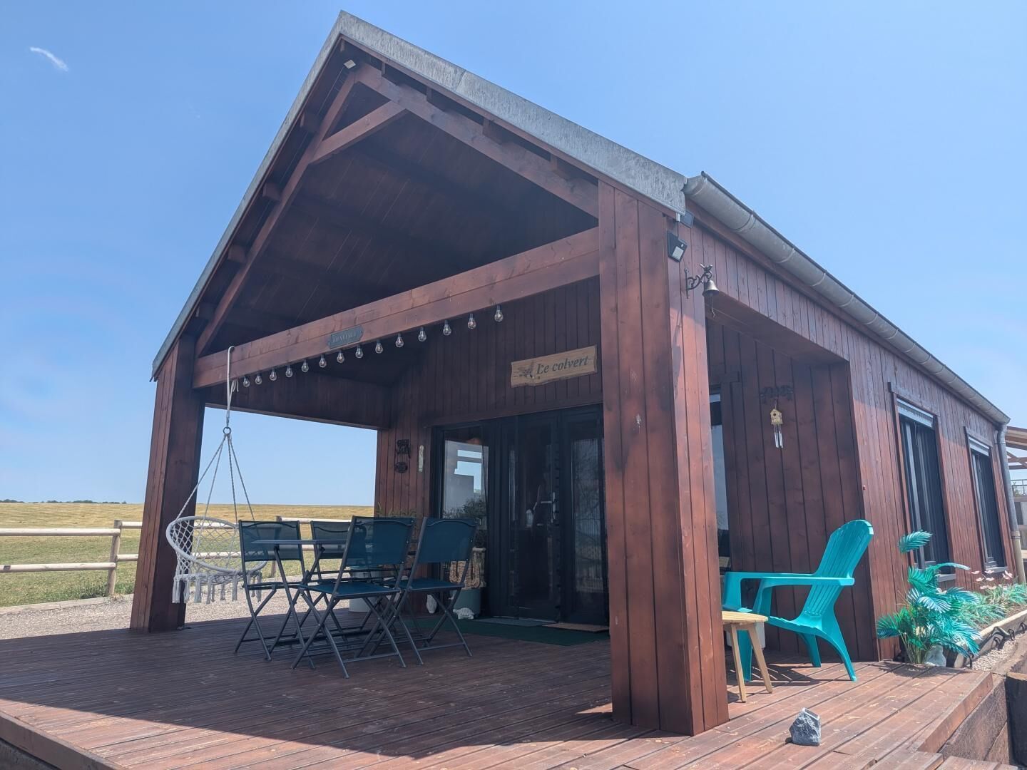 A wooden building with a covered patio area, outdoor seating, and a sign indicating a restaurant.