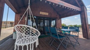 Un área de estar al aire libre con techo de madera, una silla colgante, mesas y sillas.