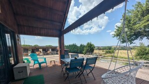 Un patio al aire libre con una mesa y sillas, una silla colgante y vistas de un establo con caballos.