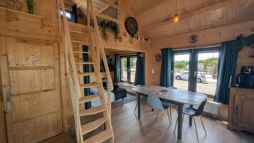 Interior de madera con zona de comedor, una escalera y vista por la puerta.