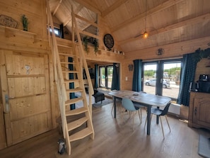 A wooden interior with a dining area, a staircase, and a view through the door. - The Mallard - ORMANCEY (ORMANCEY)