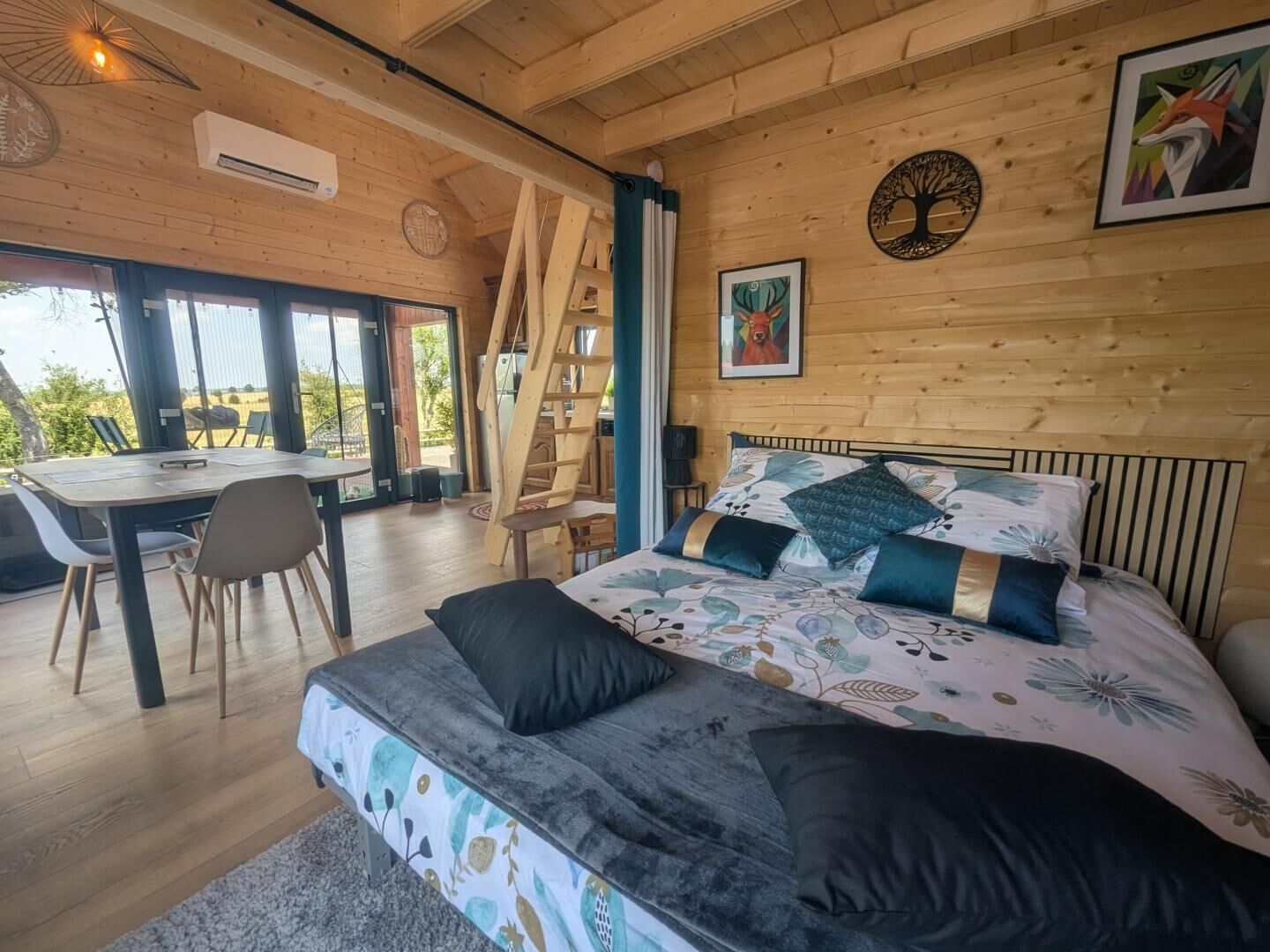 Una stanza con un letto, un tavolo, sedie, una scala e una finestra.