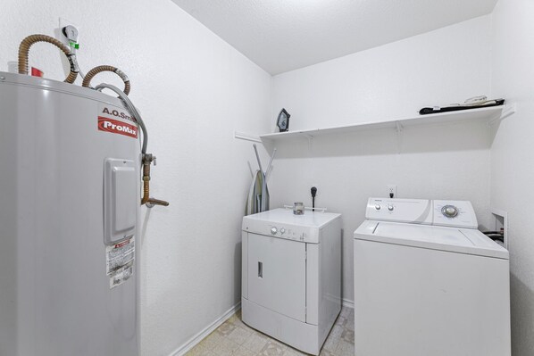 A laundry room with a water heater, a washing machine, and a dryer.