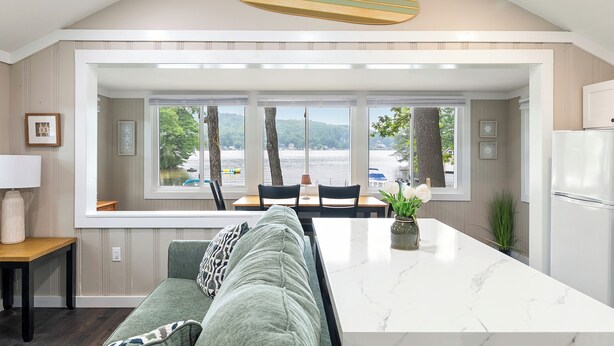 Una cocina moderna con una isla grande, comedor y vista a un lago.