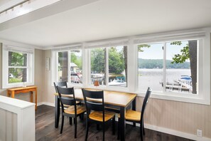 A dining area with a view of a lake and boats, featuring a table and chairs. - Cabin 41 at The Historic Sandy Point Resort w/ Boat Slip and Onsite Boat ramp (Alton)