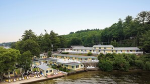 Un motel a orillas del río con varias construcciones, un muelle y una fila de sillas de playa.
