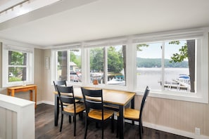 A dining area with a view of a lake and boats, featuring a table and chairs. - Cabin 42 at the Historic Sandy Point Resort W/ Boat Slip and Onsite Boat Ramp (Alton)