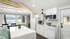 A modern kitchen with white cabinetry, a central island, and a view of the outdoors. - Cabin 42 at the Historic Sandy Point Resort W/ Boat Slip and Onsite Boat Ramp (Alton)