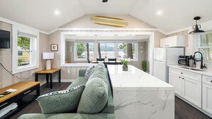 A modern kitchen with a central island, white cabinetry, and a ceiling fan. - Cabin 42 at the Historic Sandy Point Resort W/ Boat Slip and Onsite Boat Ramp (Alton)