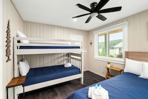 A room with bunk beds, a ceiling fan, a window with a view, and a bedside table with a plant. - Cabin 16 at Historic Sandy Point Resort W/ Boat Slip and onsite boat ramp (Alton)