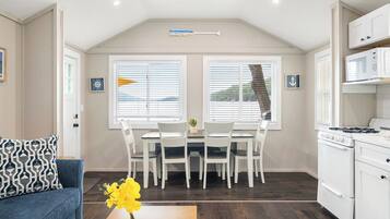 Una cocina moderna con armarios blancos, una mesa de comedor con sillas y un sofá azul.