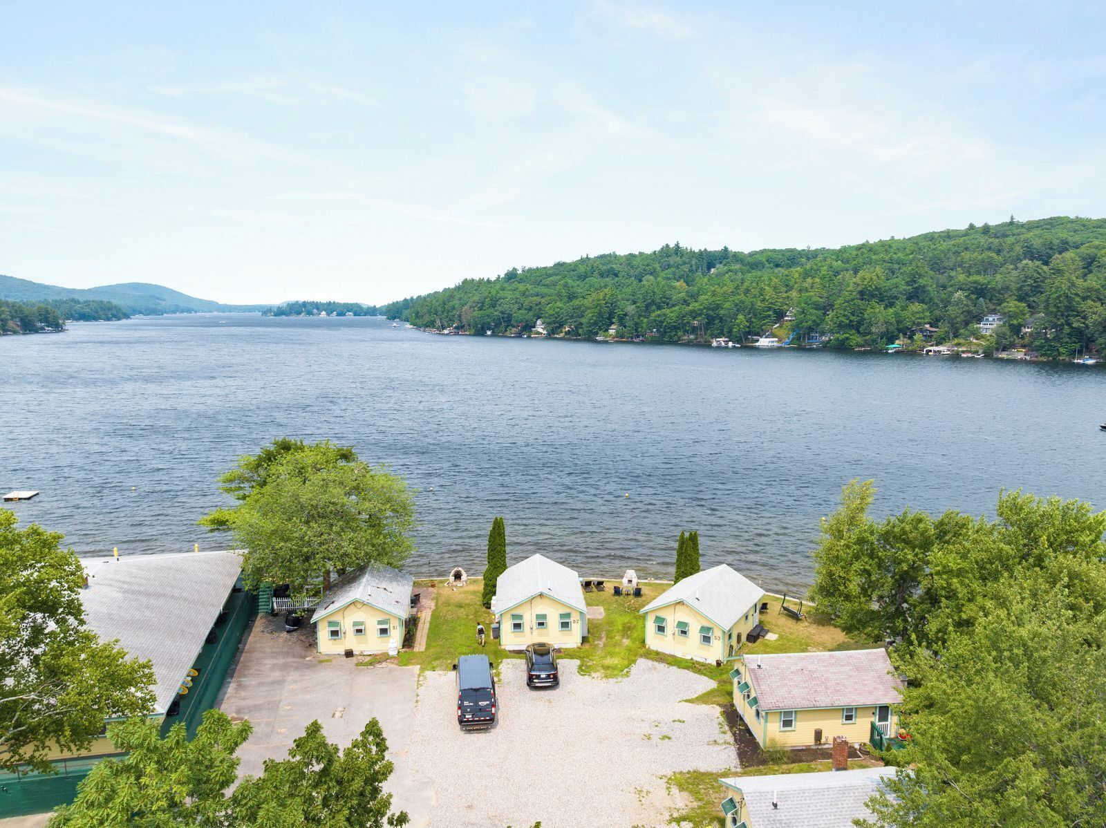 A lakeside property with multiple houses, a parking area, and a view of the lake.