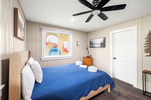 A bedroom with a bed, a ceiling fan, a window with blinds, a nightstand, and a door. - Cabin 60 at Historic Sandy Point Resort W/ Boat Slip and Onsite Boat Ramp (Alton)