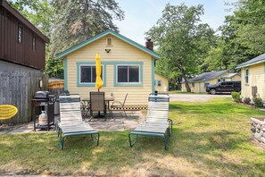 A small yellow house with a green roof, a barbecue grill, two lawn chairs, and a yellow umbrella. - Cabin 60 at Historic Sandy Point Resort W/ Boat Slip and Onsite Boat Ramp (Alton)