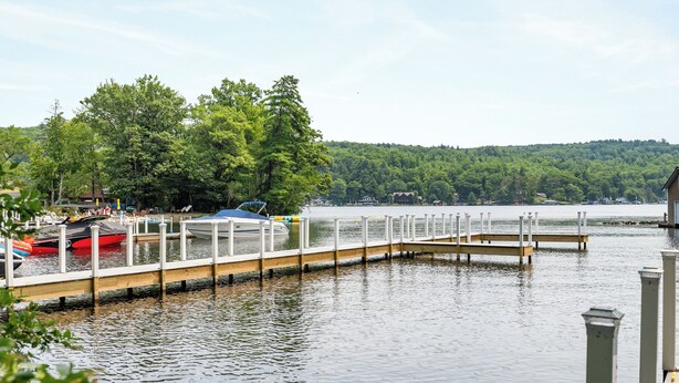 A calm lake with a wooden dock extending into the water, surrounded by lush greenery and a forested hill in the background. - Cabin 47 at Historic Sandy Point Resort W/ Boat Slip And Onsite Boat ramp (Alton)
