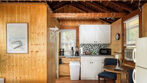 A cozy cabin interior with a wooden interior, a kitchenette, a dining area, and a bed. - Cabin 47 at Historic Sandy Point Resort W/ Boat Slip And Onsite Boat ramp (Alton)