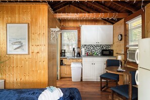 Ein gemütliches Blockhaus-Interieur mit Holzausstattung, einer Küchenzeile, einem Essbereich und einem Bett.