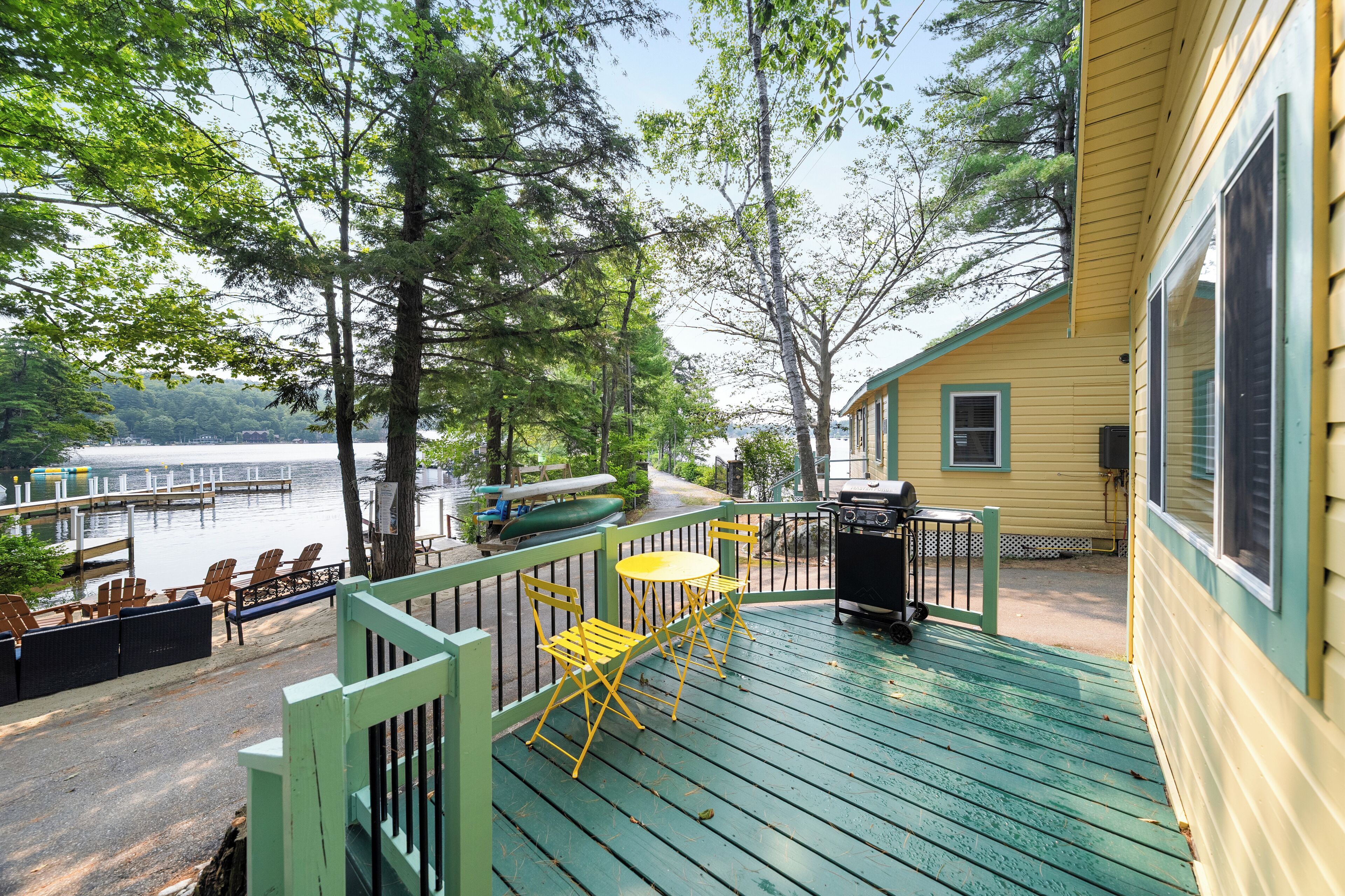 A deck with outdoor seating, a grill, and a view of a lake.
