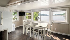 A kitchen with a dining area, large windows, and a view of a lake. - Cabin 48 at Historic Sandy Point Resort W/ Boat Slip and Onsite Boat Ramp (Alton)