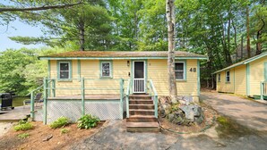 A small yellow cabin with a green porch, a set of stairs leading to the door, and a number '48' on the side. - Cabin 48 at Historic Sandy Point Resort W/ Boat Slip and Onsite Boat Ramp (Alton)