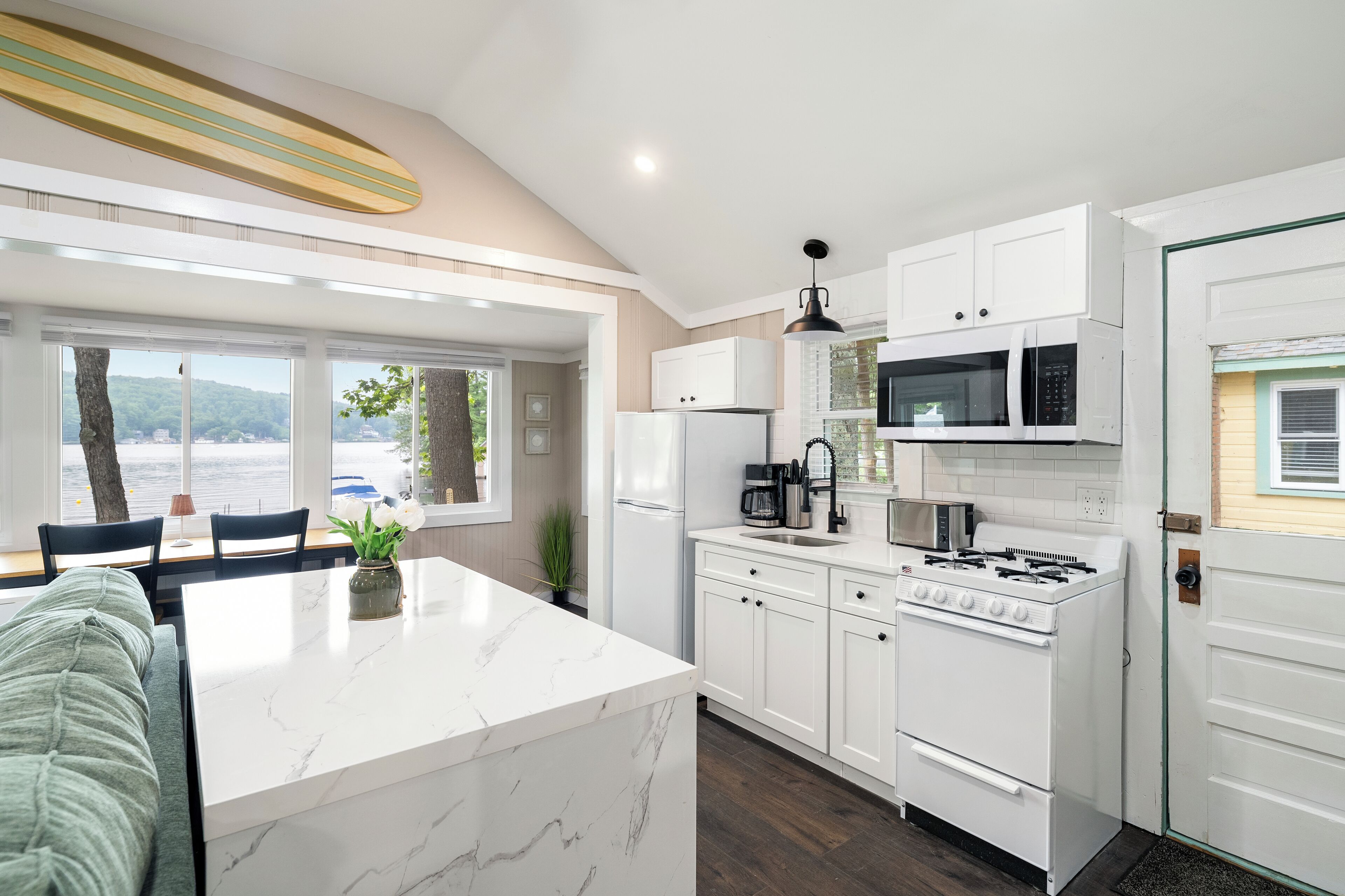 Een moderne keuken met witte kasten, een centraal eiland en uitzicht op de omgeving.