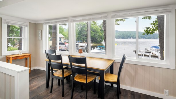 A dining area with a view of a lake and boats, featuring a table and chairs. - Cabin 45 at Historic Sandy Point Resort W/ Boat Slip and Onsite Boat Ramp (Alton)