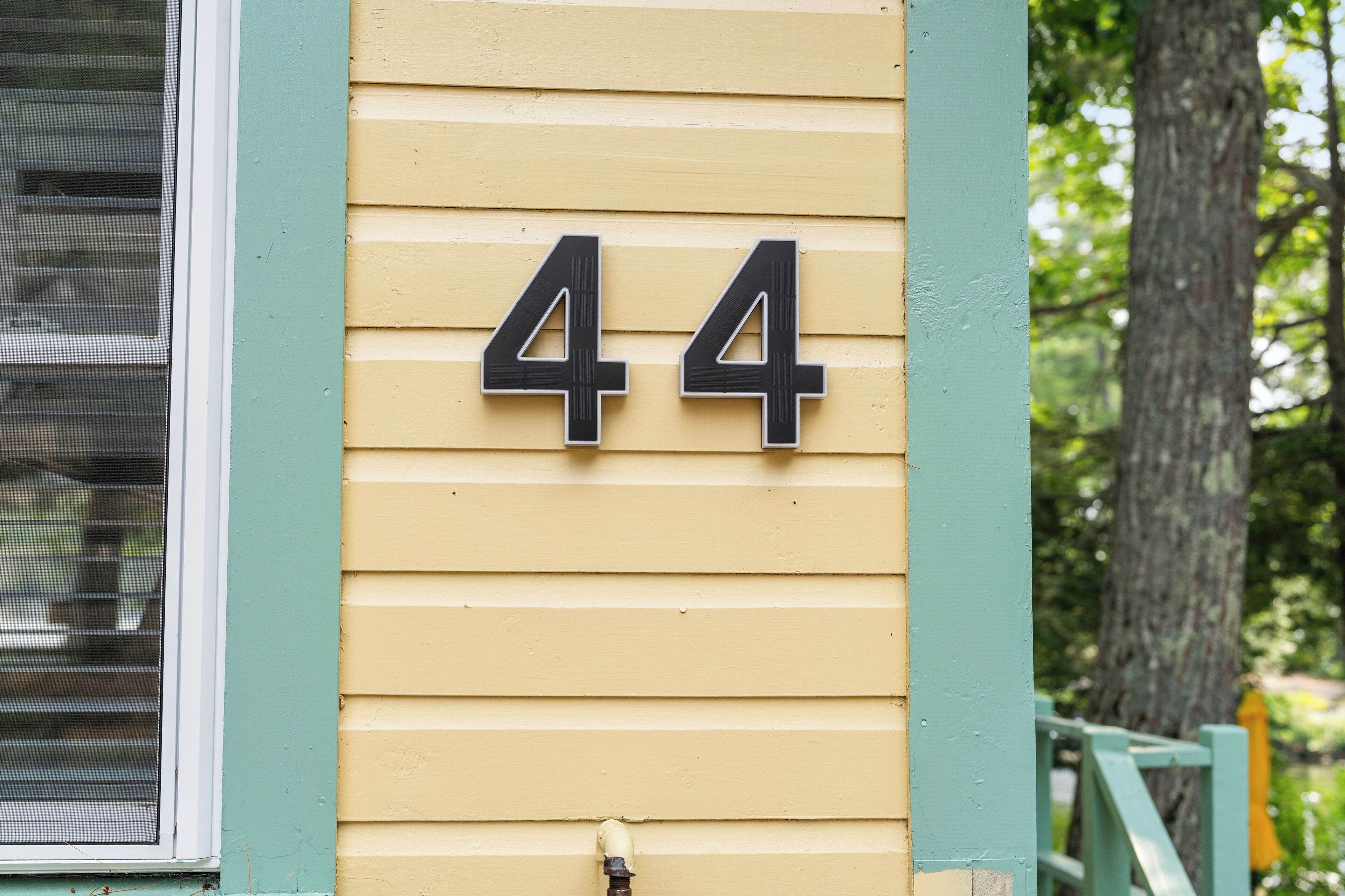 A house number 44 on a yellow siding wall.