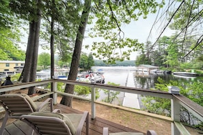 Eine Terrasse mit Sitzgelegenheiten im Freien mit Blick auf einen ruhigen Fluss, an dessen Ufer Boote liegen.